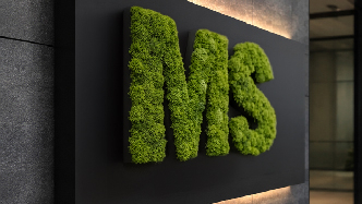 Close-up of green preserved moss letters used as a company logo on a black wall panel
