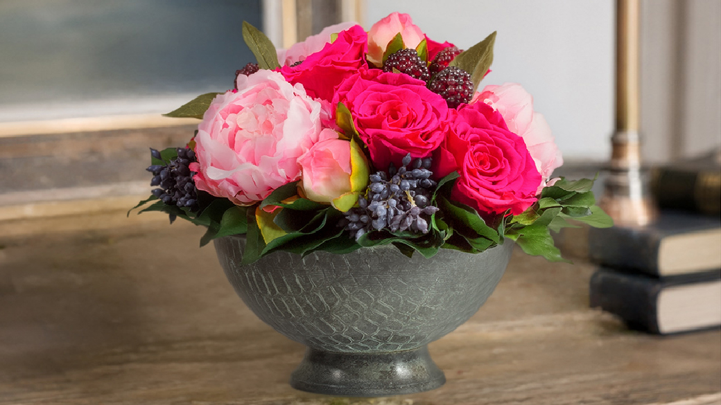 Pinkfarbenes Blumengesteck mit konservierten Infinity Rosen, Pfingstrosen und Efeu in einer Schale aus oxidiertem Messing