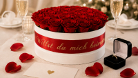 Rosenbox mit roten konservierten Rosen, personalisiertem Satinband und Verlobungsring für einen Hochzeitsantrag