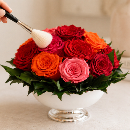 Composition de roses éternelles rouges, roses et orange dépoussiérée délicatement à l’aide d’un pinceau doux.