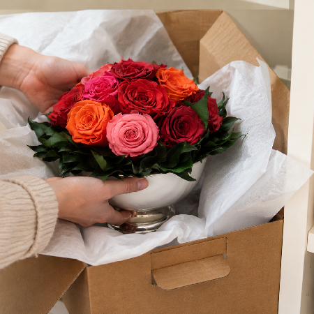 Infinity Rosen Gesteck mit roten, rosa und orangefarbenen Rosen wird vorsichtig mit einem weichen Pinsel entstaubt