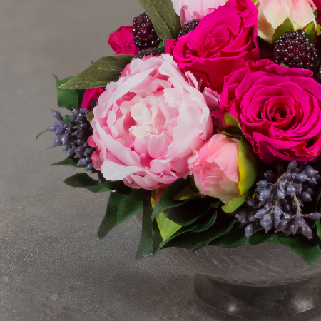 Detail der Schale aus oxidiertem Messing mit konserviertem Efeu und floralen Elementen des pinken Blumengestecks