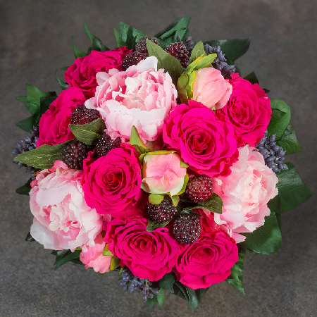 Blumengesteck aus der Vogelperspektive mit pinken Infinity Rosen, rosafarbenen Pfingstrosen, Beeren und Efeu