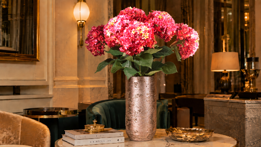 Pinkfarbene Kunsthortensie in einer eleganten Vase mit cremefarbenen Accessoires