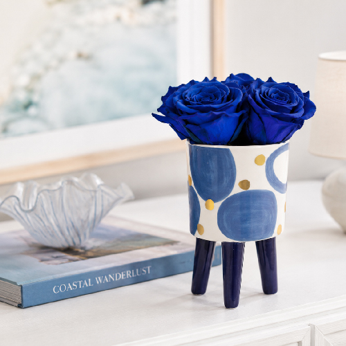 Blaue Infinity Rosen als maritime Dekoration Blaue Infinity Rosen im maritimen Keramikgefäß auf einem hellen Sideboard