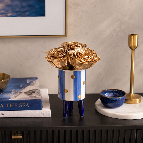 Goldfarbene Infinity Rosen als maritime Dekoration Goldfarbene Infinity Rosen im maritimen Keramikgefäß auf einer eleganten Konsole
