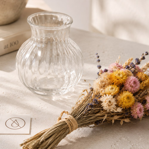 Trockenblumen neben einer trockenen Glasvase als Hinweis, dass sie kein Wasser benötigen